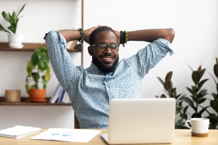 Man-in-glasses-smiling-behind-desk-with-laptop Man in glasses smiling behind desk with laptop